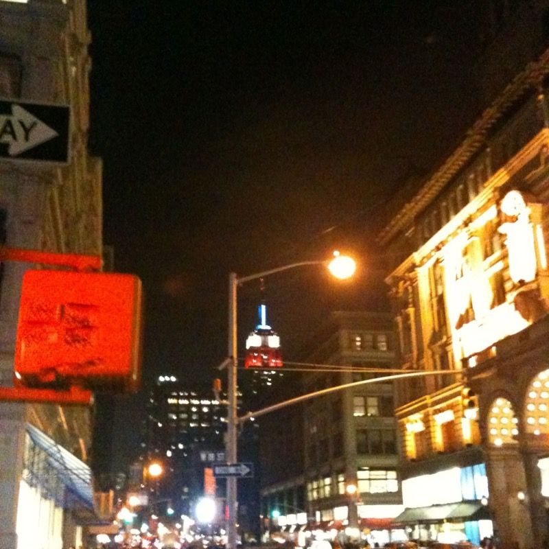 Manhattan street at night, the lit Empire State Building in the distance