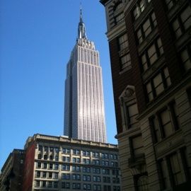 The Empire State Building on a clear day, framed by older buildings